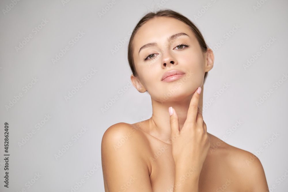 Beautiful Young Woman with Clean Fresh Skin standing over light grey background Beautiful Young Woman with Clean Fresh Skin standing over light grey background