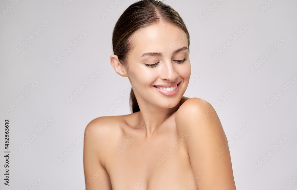 Beautiful Young Woman with Clean Fresh Skin standing over light grey background Beautiful Young Woman with Clean Fresh Skin standing over light grey background