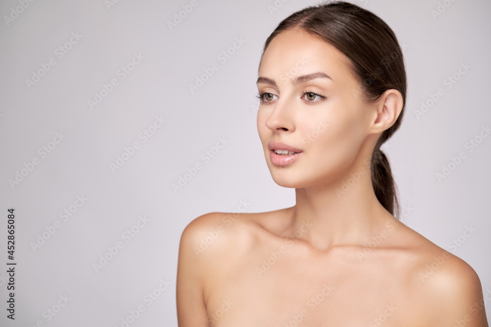 Beautiful Young Woman with Clean Fresh Skin standing over light grey background Beautiful Young Woman with Clean Fresh Skin standing over light grey background