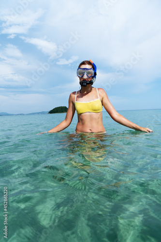 Girl snorkeling with snorkel and mask in clear sea water on the beach.