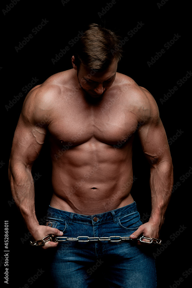 Handsome muscular man, topless, posing in studio. Bodybuilder. Beautiful body. Dark background Handsome muscular man, topless, posing in studio. Bodybuilder. Beautiful body. Dark background