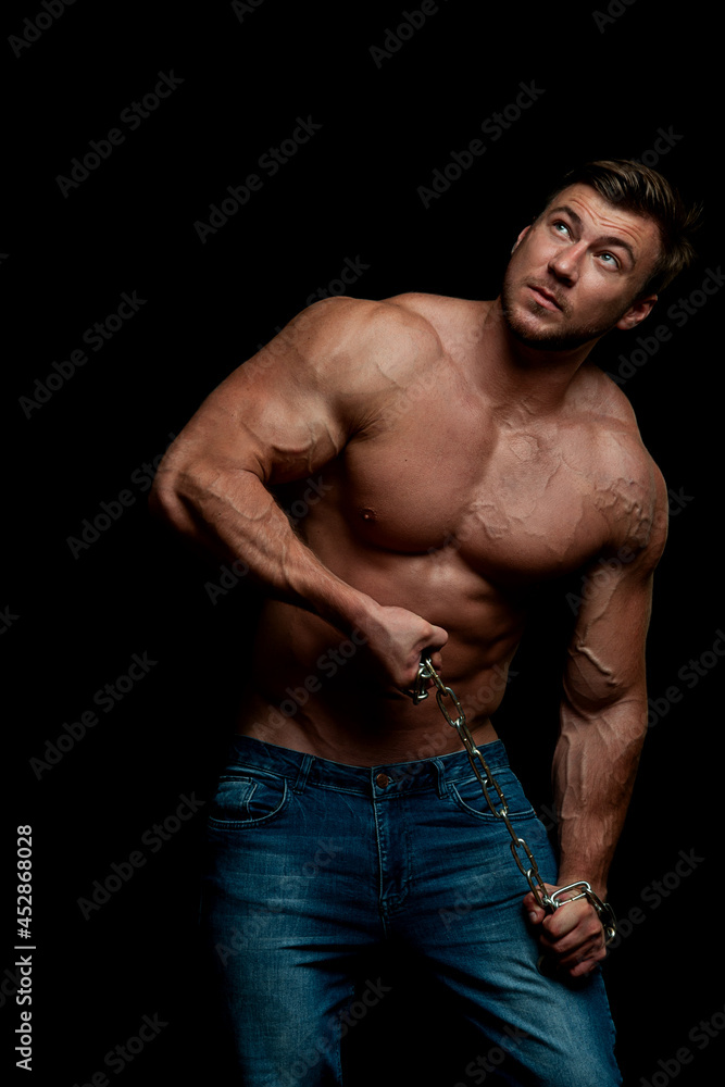 Handsome muscular man, topless, posing in studio. Bodybuilder. Beautiful body. Dark background Handsome muscular man, topless, posing in studio. Bodybuilder. Beautiful body. Dark background