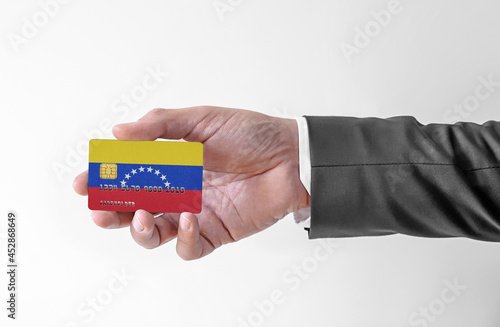 Bank credit plastic card with flag of Venezuela holding man in elegant suit