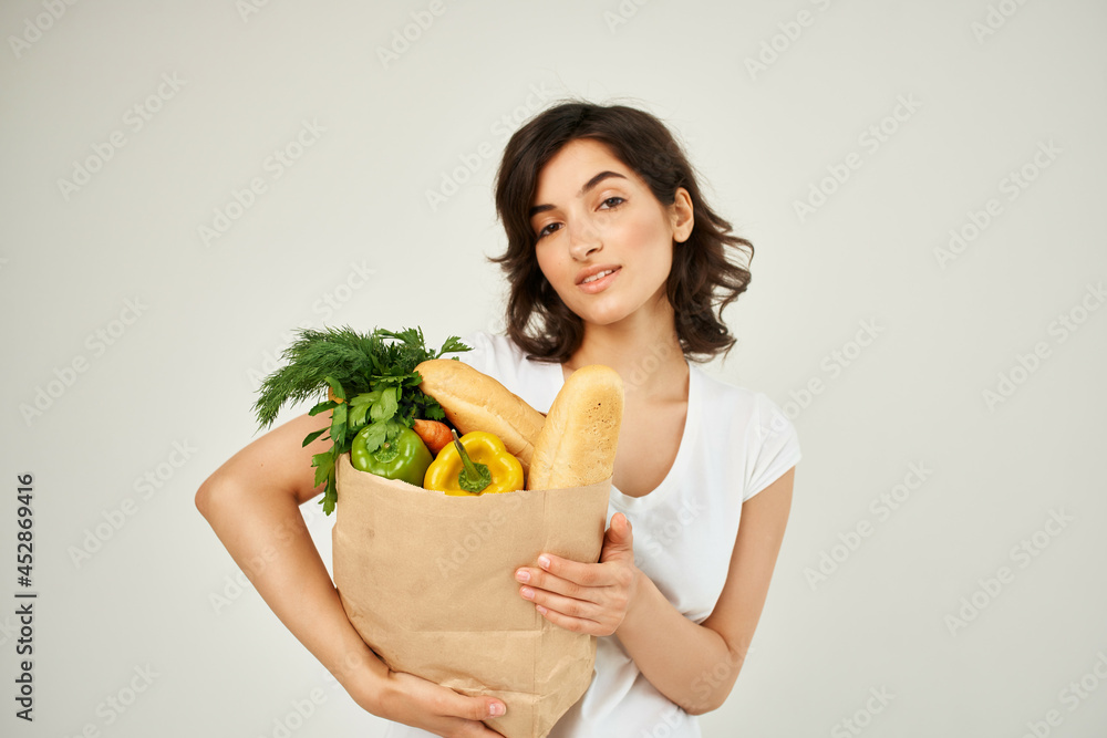 brunette in a white t-shirt packs food vegetables delivery brunette in a white t-shirt packs food vegetables delivery