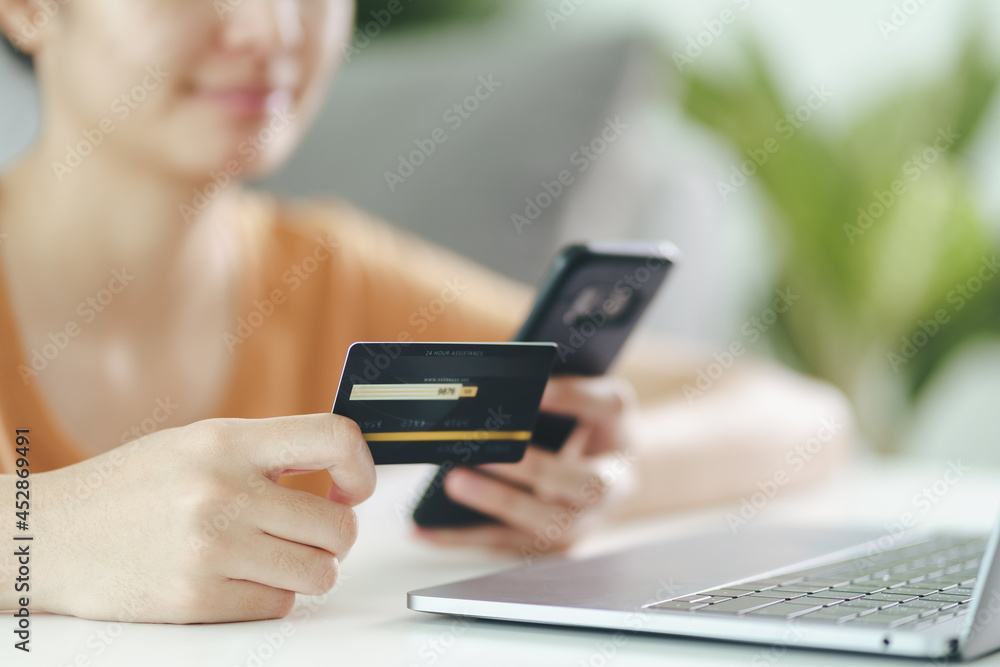 Young woman holding credit card and using smart phone for online shopping, internet banking, e-commerce, spending money, working from home concept Young woman holding credit card and using smart phone for online shopping, internet banking, e-commerce, spending money, working from home concept