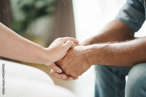 Female friend or family sitting and hold hands during cheer up to mental depress man, Psychologist provides mental aid to patient. PTSD Mental health concept.