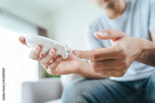 Asian man checking blood sugar level by Digital Glucose meter, Healthcare and Medical, diabetes, glycemia concept
