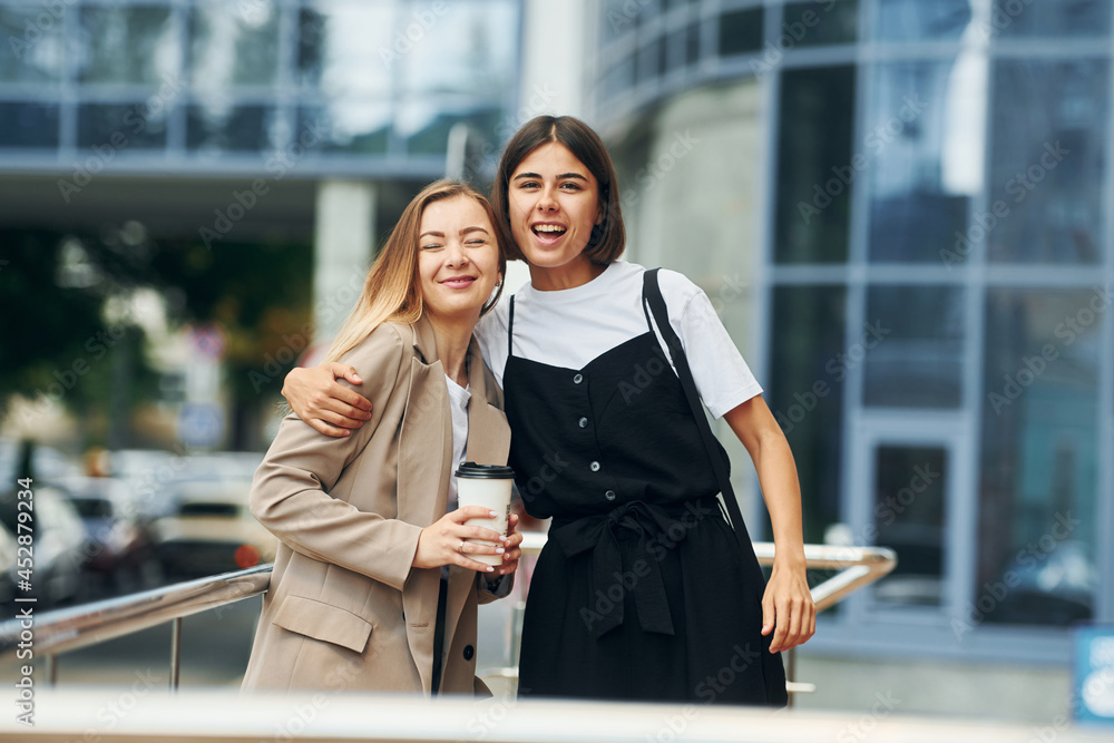 Good friends. Women in formal wear is outdoors in the city together Good friends. Women in formal wear is outdoors in the city together