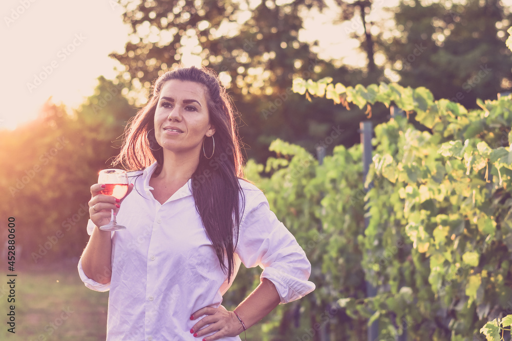 Young beautiful smiling woman sitting with a cat in a Vineyard with a glass of rose wine. Woman playing with cat during the summer vacation Young beautiful smiling woman sitting with a cat in a Vineyard with a glass of rose wine. Woman playing with cat during the summer vacation