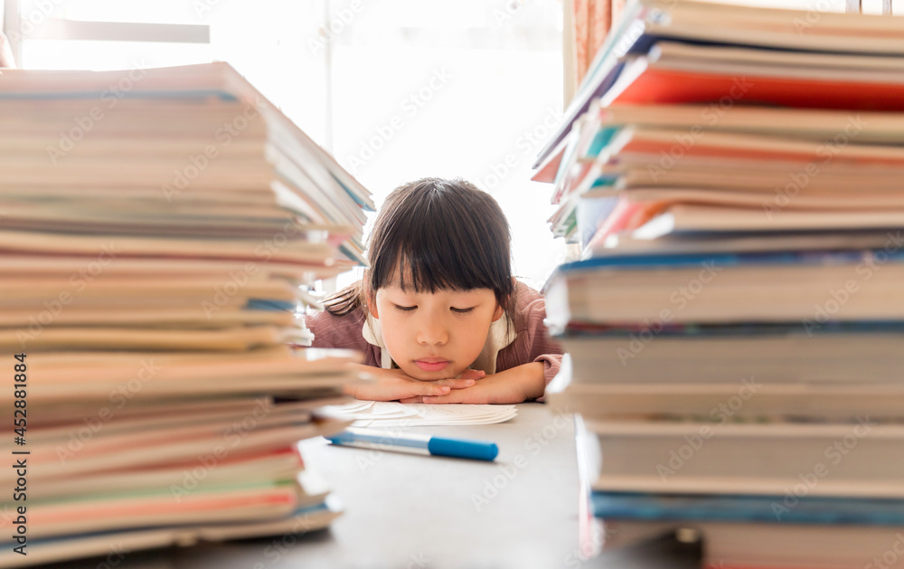 夏休みの大量の宿題に悩んでいる小学生の子供の様子 夏休みの大量の宿題に悩んでいる小学生の子供の様子