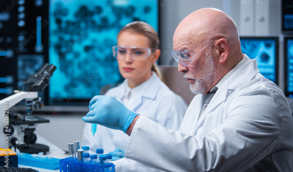 Professor and doctor work in a modern scientific laboratory using equipment and computertechnologies. Group of scientists make research and develop new vaccines. Science and healthcare concept. Professor and doctor work in a modern scientific laboratory using equipment and computertechnologies. Group of scientists make research and develop new vaccines. Science and healthcare concept.