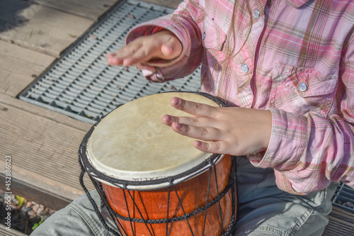 the girl child with a djembe drum outdoor on the porch of the house photo without processing