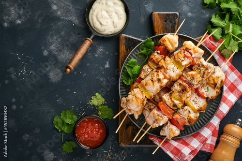 Chicken shish kebab or skewers kebab on wooden board, spices, herbs and vegetables on dark grey background. Barbecue Raw ingredients for goulash or shish kebab. Top view. Free copy space.