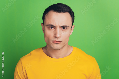 Portrait of serious masculine guy look camera on green background