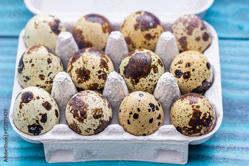 Wachteleier in einer Eierpackung vor einem blauen Hintergrund aus Holz