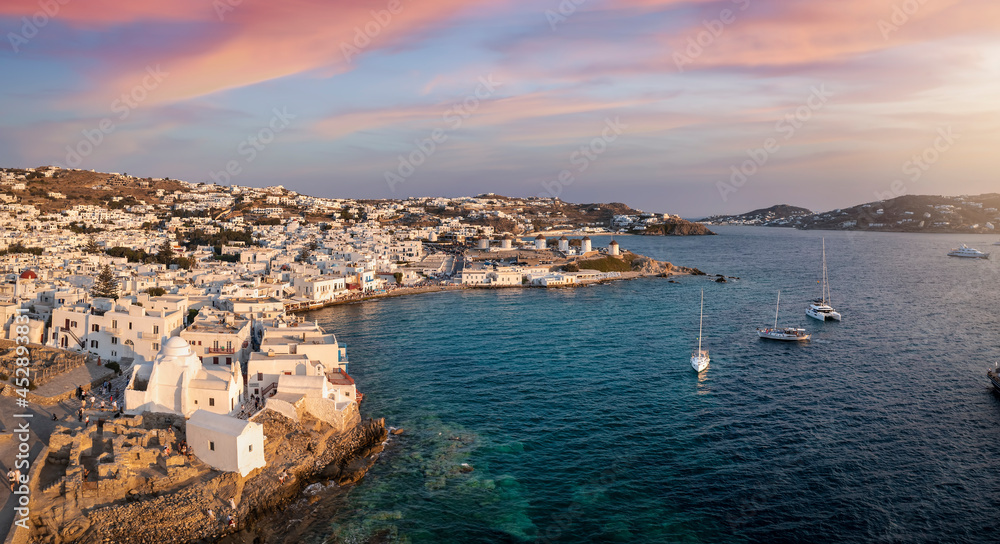 Panoramic aerial view to the town of Mykonos island with little Venice district and the famous windmills during sunset time, Greece