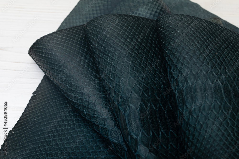 Dark blue dyed genuine natural python leather on the wooden table
Dark blue dyed genuine natural python leather on the wooden table