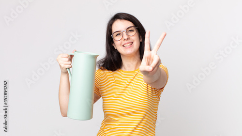 Fotografie pretty woman smiling and looking happy, gesturing victory or peace and holding a