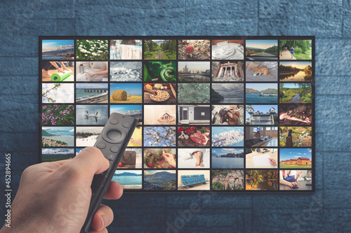 VOD service on television. TV streaming concept. man holding remote control with many icons of video service on demand on background Oline TV VOD provider. photo