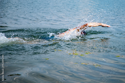 man swimming in open water lake