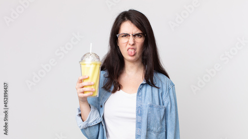 pretty woman feeling disgusted and irritated and tongue out and holding a vanilla milkshake