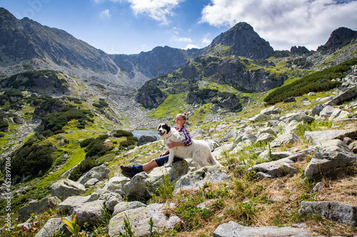 Photography woman with white dog sitting on mountain top in summer landscape slow travel and