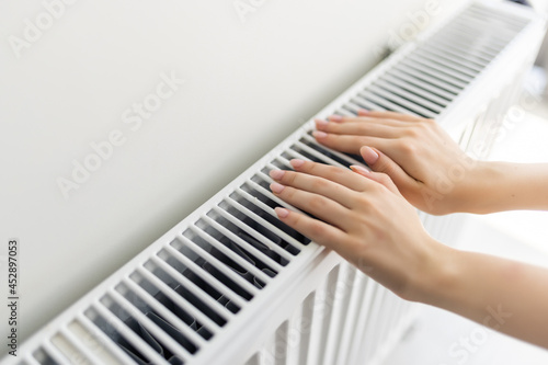 Young Woman's Hand Adjusting Heater Thermostat in winter time