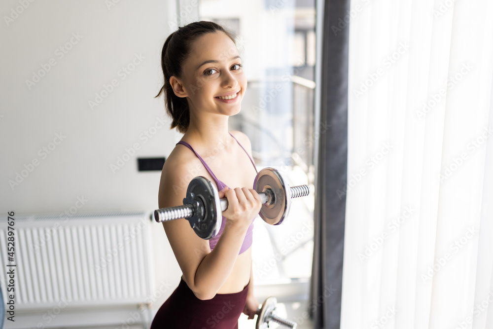 Active athletic woman with dumbbells pumping up muscles biceps concept fitness sport training lifestyle Active athletic woman with dumbbells pumping up muscles biceps concept fitness sport training lifestyle