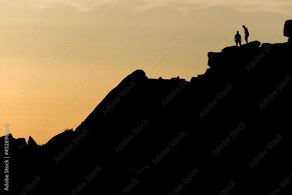 Two rock climbers look back from the summit of stanage edge in england