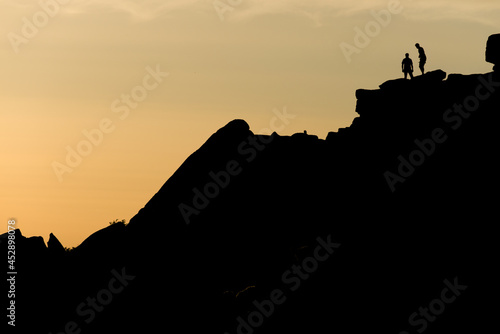 Two rock climbers look back from the summit of stanage edge in england