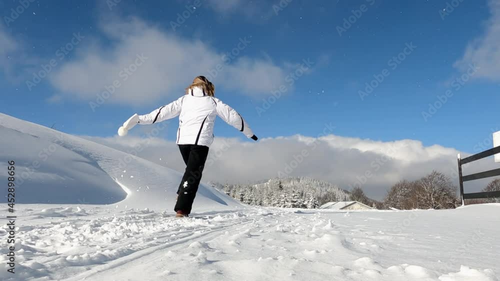 Young happy joyful woman with open arms running on the snowy winter mountain during a skiing holiday on a sunny winter day. Slow motion Young happy joyful woman with open arms running on the snowy winter mountain during a skiing holiday on a sunny winter day. Slow motion