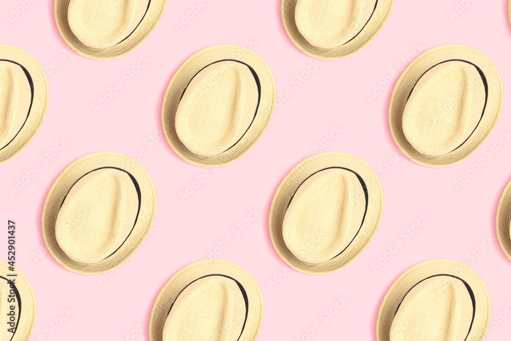 Pattern made of straw hats on a pink pastel background. Summer layout concept.