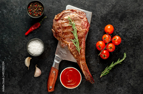 grilled Tomahawk steak, on a knife with spices on a stone background