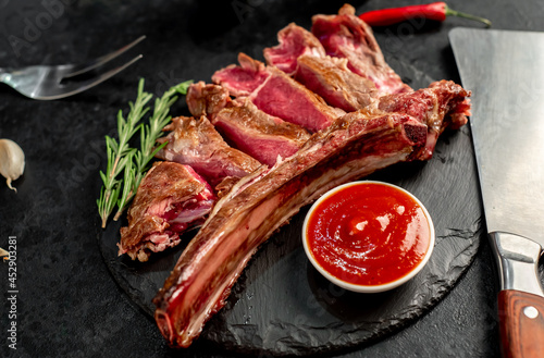 grilled Tomahawk steak with spices on a stone background 