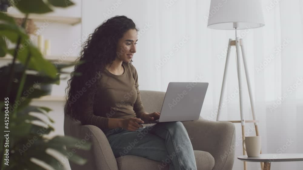 Happy lifestyle. Young relaxed lady freelancer working remotely on laptop from home, tracking shot, slow motion Happy lifestyle. Young relaxed lady freelancer working remotely on laptop from home, tracking shot, slow motion