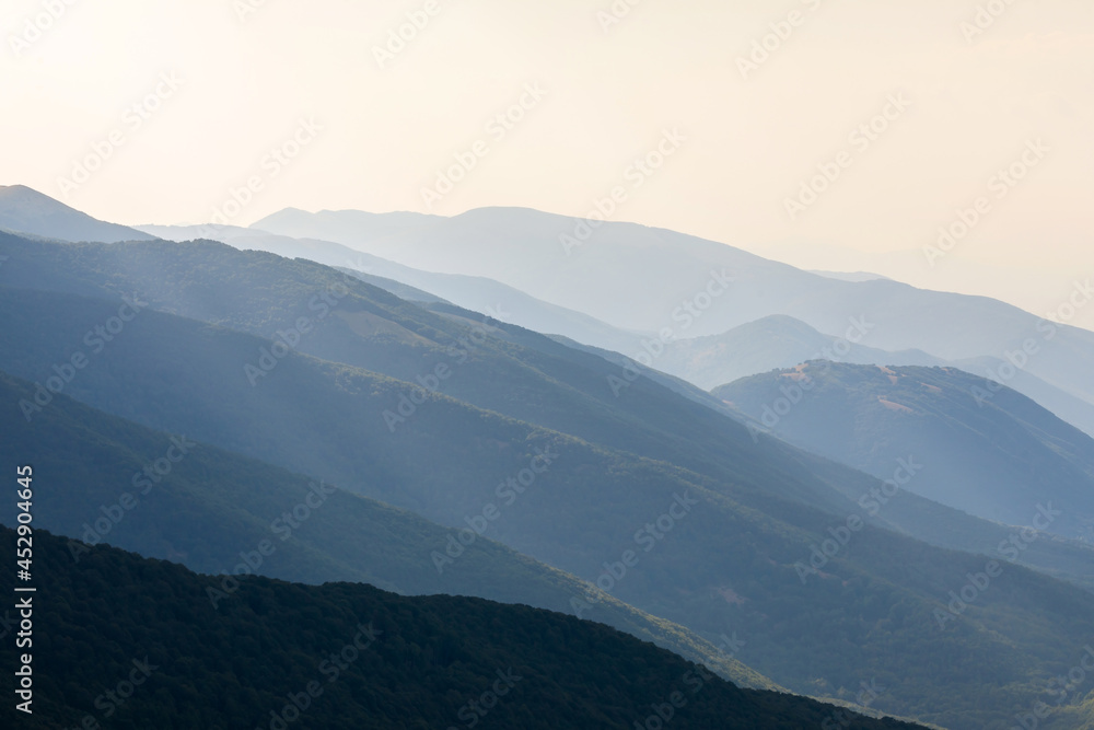 Fototapeta premium Rays of light illuminate the mountain peaks. Mountain peaks illuminated by sunlight create a beautiful landscape for a natural backdrop.