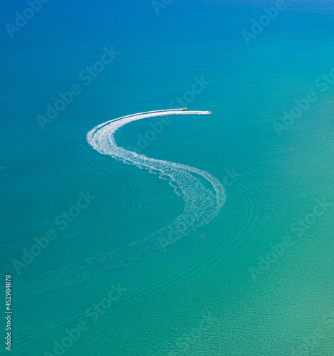 Watersports at the beach. Speedboat and wave slider leaving zigzag trail on water, view from above