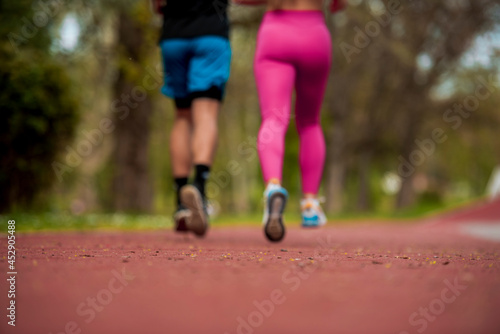 Attractive young competitive couple running together outdoors at a park