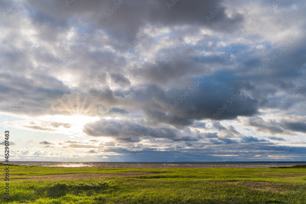 Sun rays through cloudy sky over the North Sea at sunset. Autumn, seascape view background. 