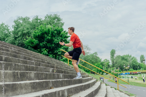Fit male athlete performing stairs workout, running up climbing stairs performing outdoor track cardio.. © qunica.com