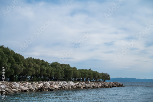 Scenic landscape of Aegean sea and hills. Athens, Greece. Cloudy day. Green trees on stone shore. photo