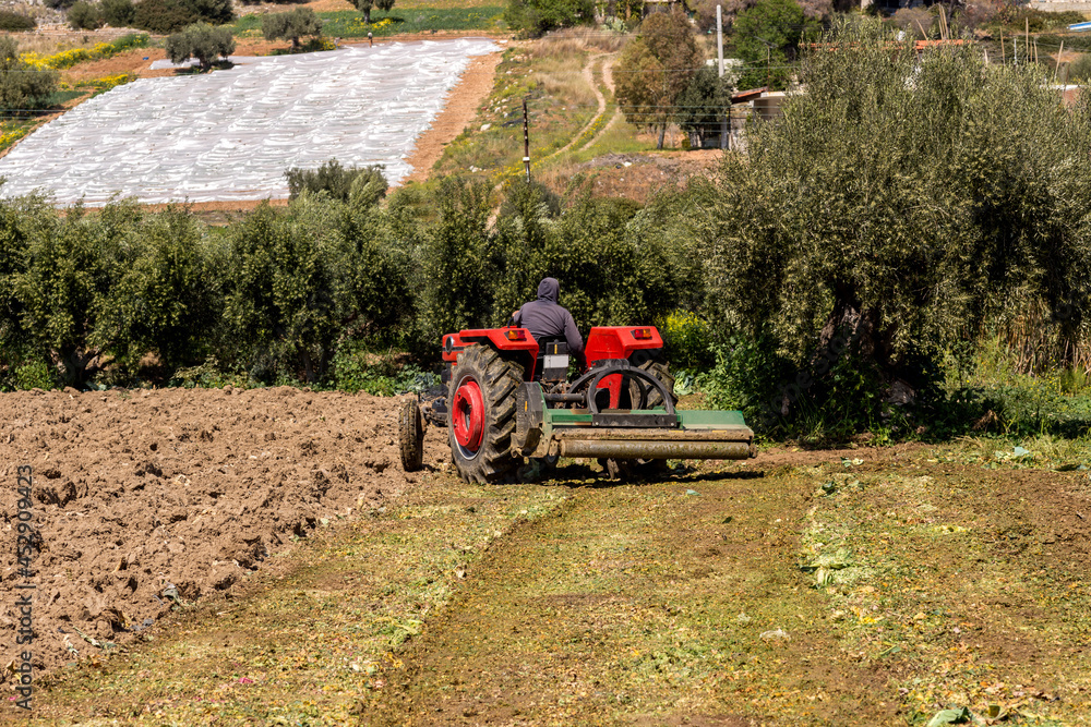 Obraz premium Farmland and tractor working the land on a sunny, spring day