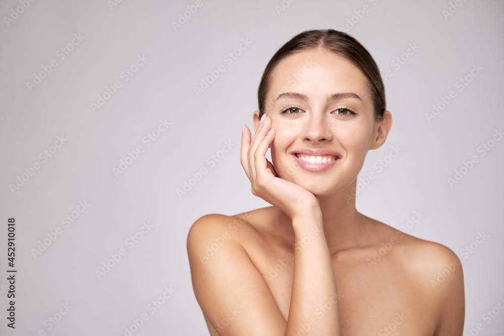Beautiful Young Woman with Clean Fresh Skin standing over light grey background Beautiful Young Woman with Clean Fresh Skin standing over light grey background