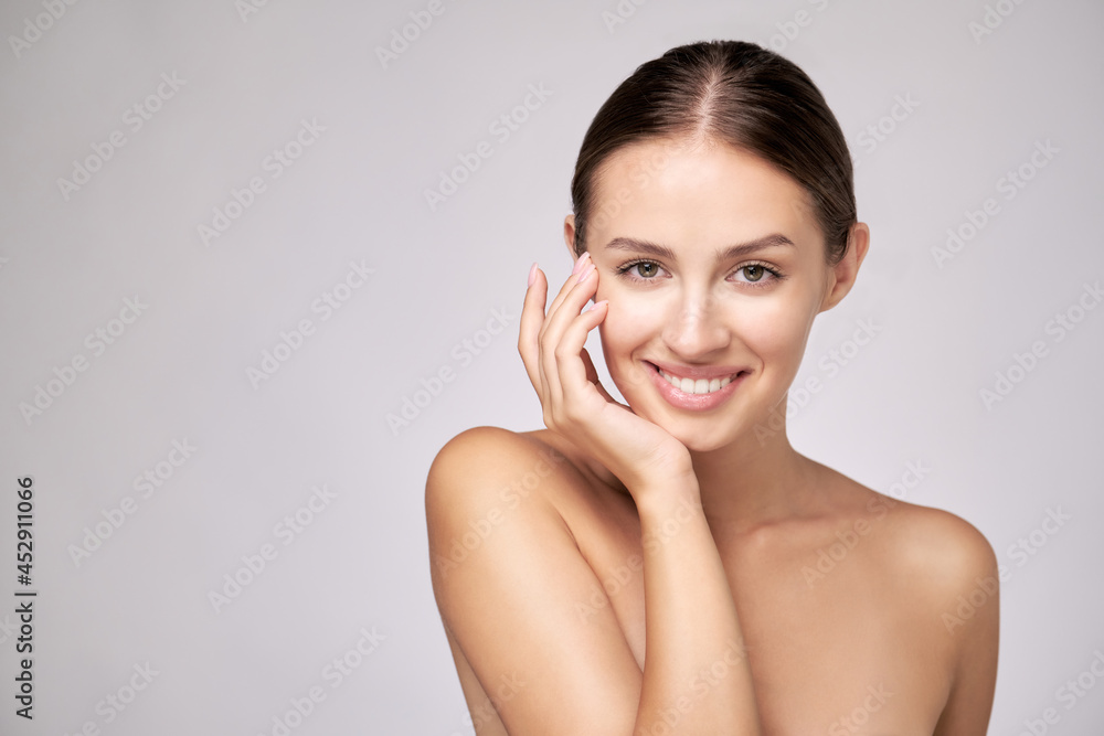 Beautiful Young Woman with Clean Fresh Skin standing over light grey background