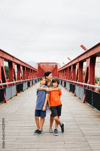 Family portrait with a middle age woman and two young boys on a red metal bridge photo