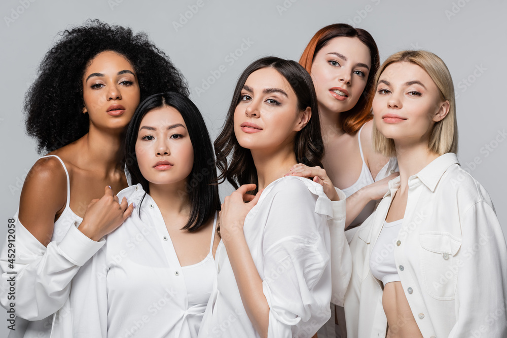 asian and curly african american models in white shirts posing with women isolated on grey asian and curly african american models in white shirts posing with women isolated on grey