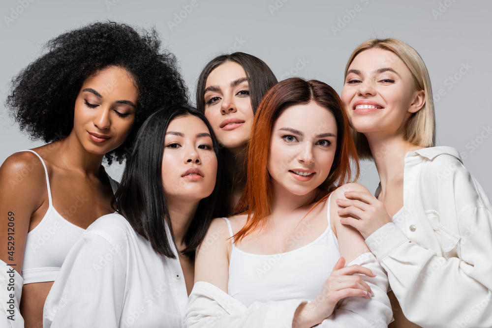 asian and african american models in white shirts posing with cheerful women isolated on grey asian and african american models in white shirts posing with cheerful women isolated on grey