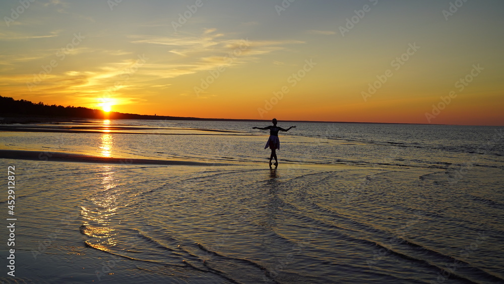 Fototapeta premium silhouette of a woman on the beach at sunset