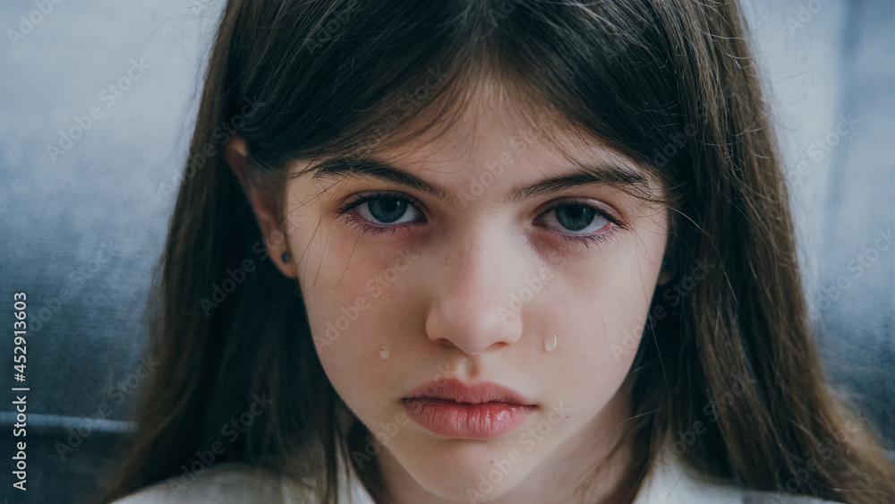 portrait of a sad beautiful girl with blue eyes and tears on her cheeks