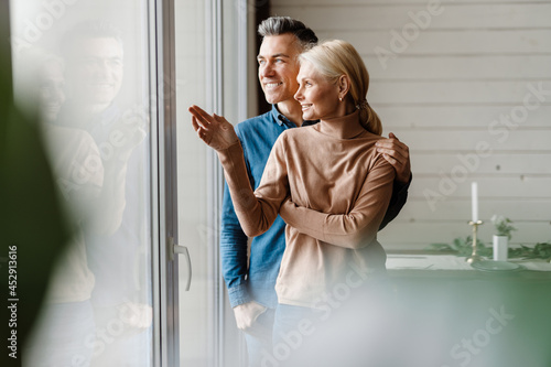 Bild auf Leinwand Happy mid aged white couple standing in modern living